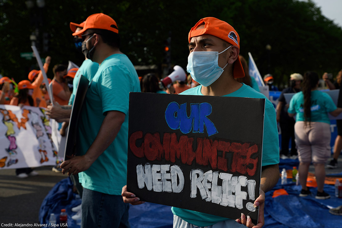 An activist holds sign that reads "Our Communities Need Relief" for immigration reform at a sit-in protest in downtown Washington, D.C.