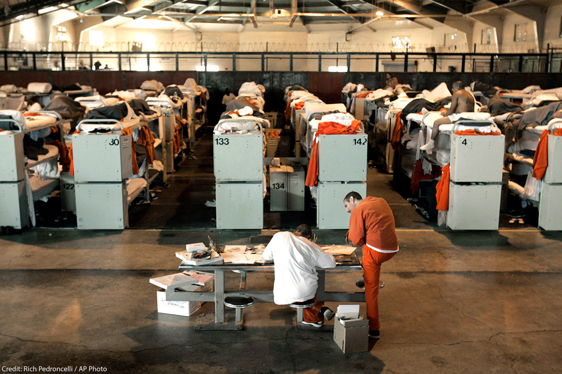 People in prison housed in a room with three-tiered bunk beds.