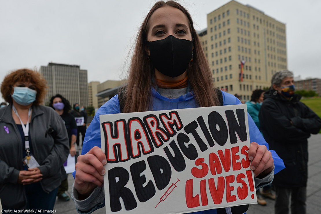 Edmontonian with a sign that reads "harm reduction saves lives," photos of loved ones and crosses with purple ribbons and hearts gather for International Overdose Awareness Day at Capital Plaza outside the Federal Building.