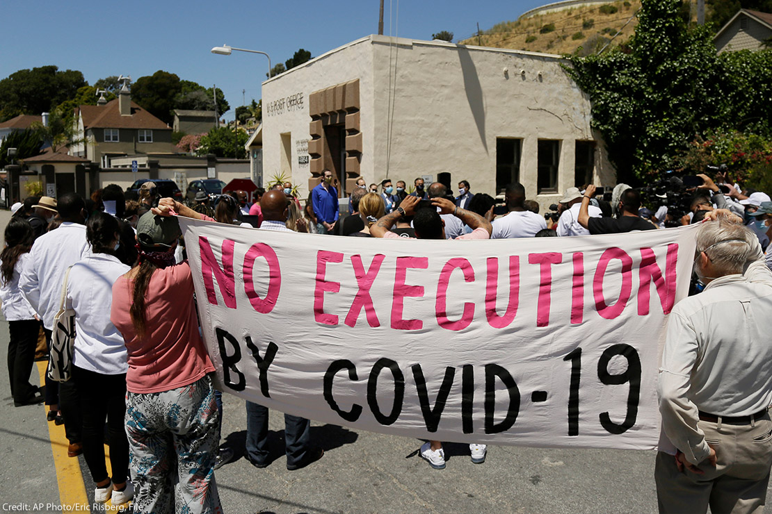 People hold up a banner saying "No Execution by Covid-19."