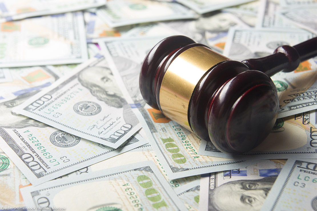 A judges' gavel on a U.S. dollar cash background, top view, close-up.