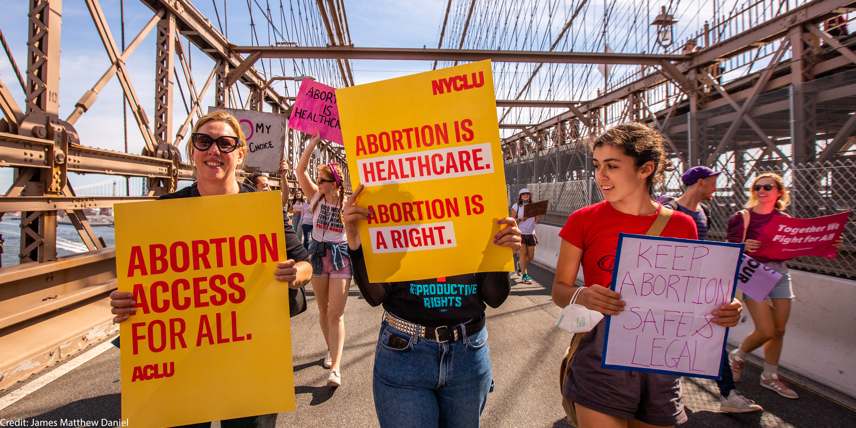 Three demonstrators holding pro-abortion signage.