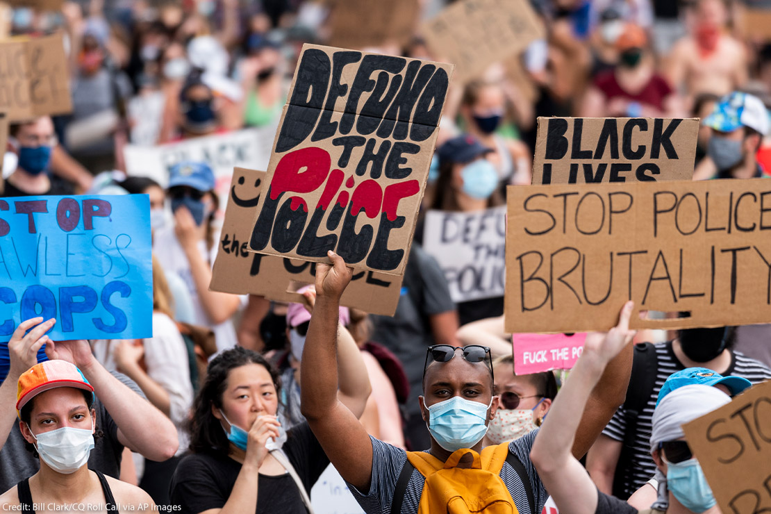 Protestors march down Pennsylvania Avenue holding signs that read “Defund the Police” and “Stop Police Brutality” among other signs.