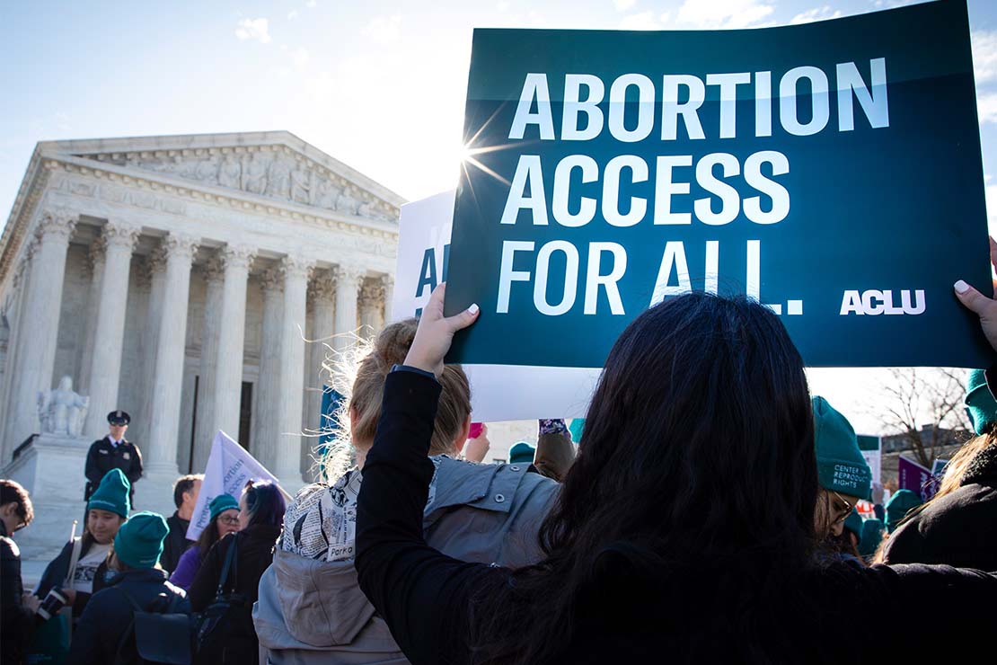 A protestor holds aloft a sign that says "Abortion Access for All" in front of the Supreme Court building in Washington, DC