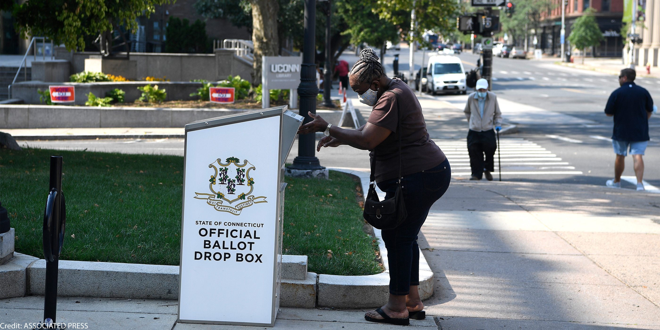 An Afrian-American woman drops a ballot into a State of Connecticut Official Ballot Drop Box outside Hartford City Hall.