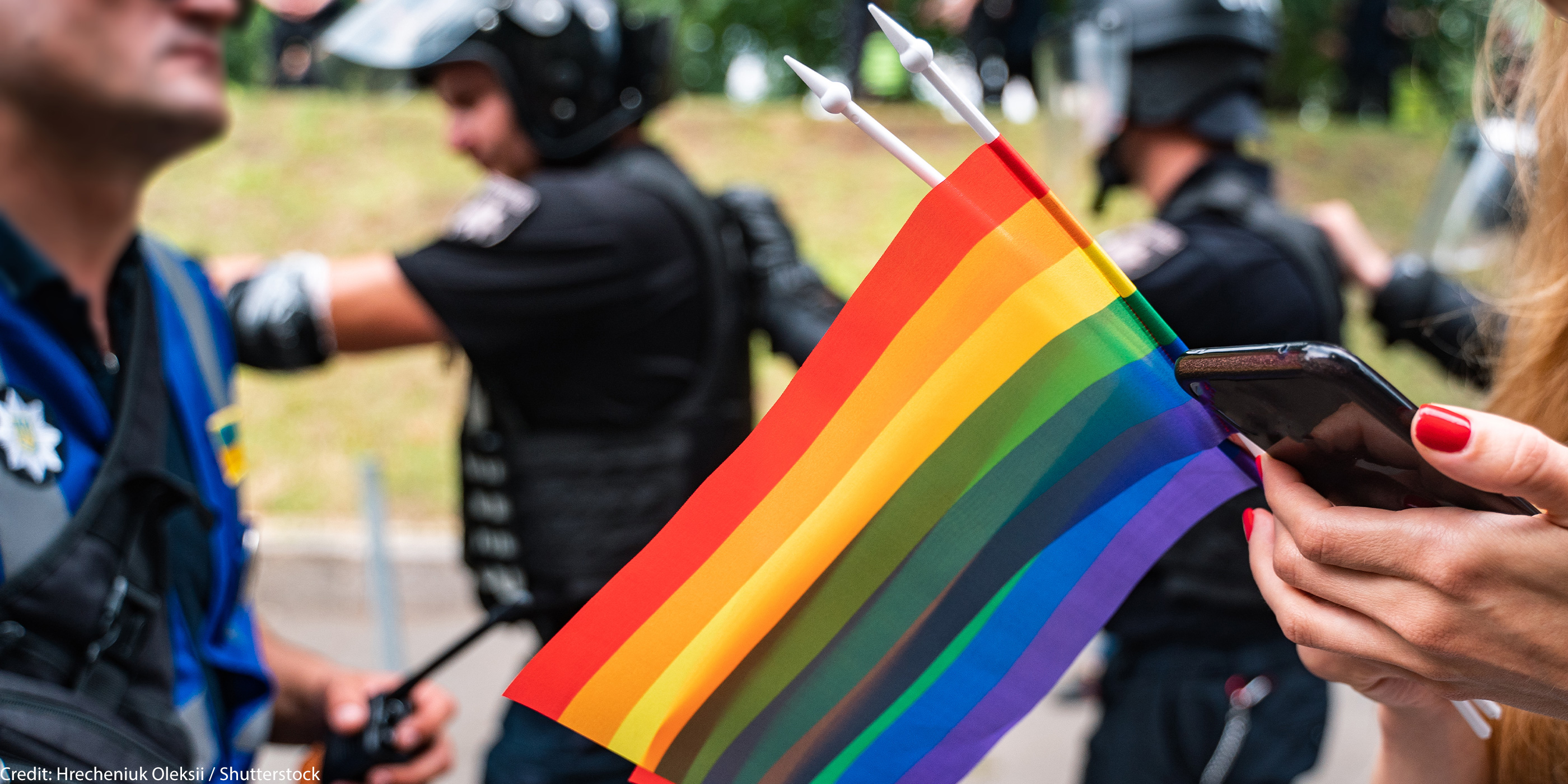 LGBTQ flag with police in the background.