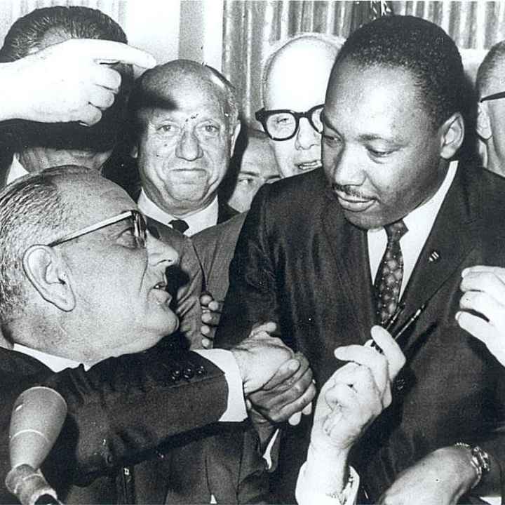 President Lyndon Johnson shakes the hand of Dr. Martin Luther King Jr., as he hands him a pen at the signing of the Civil Rights Act of 1964 on Thursday, July 2, 1964 at The White House.