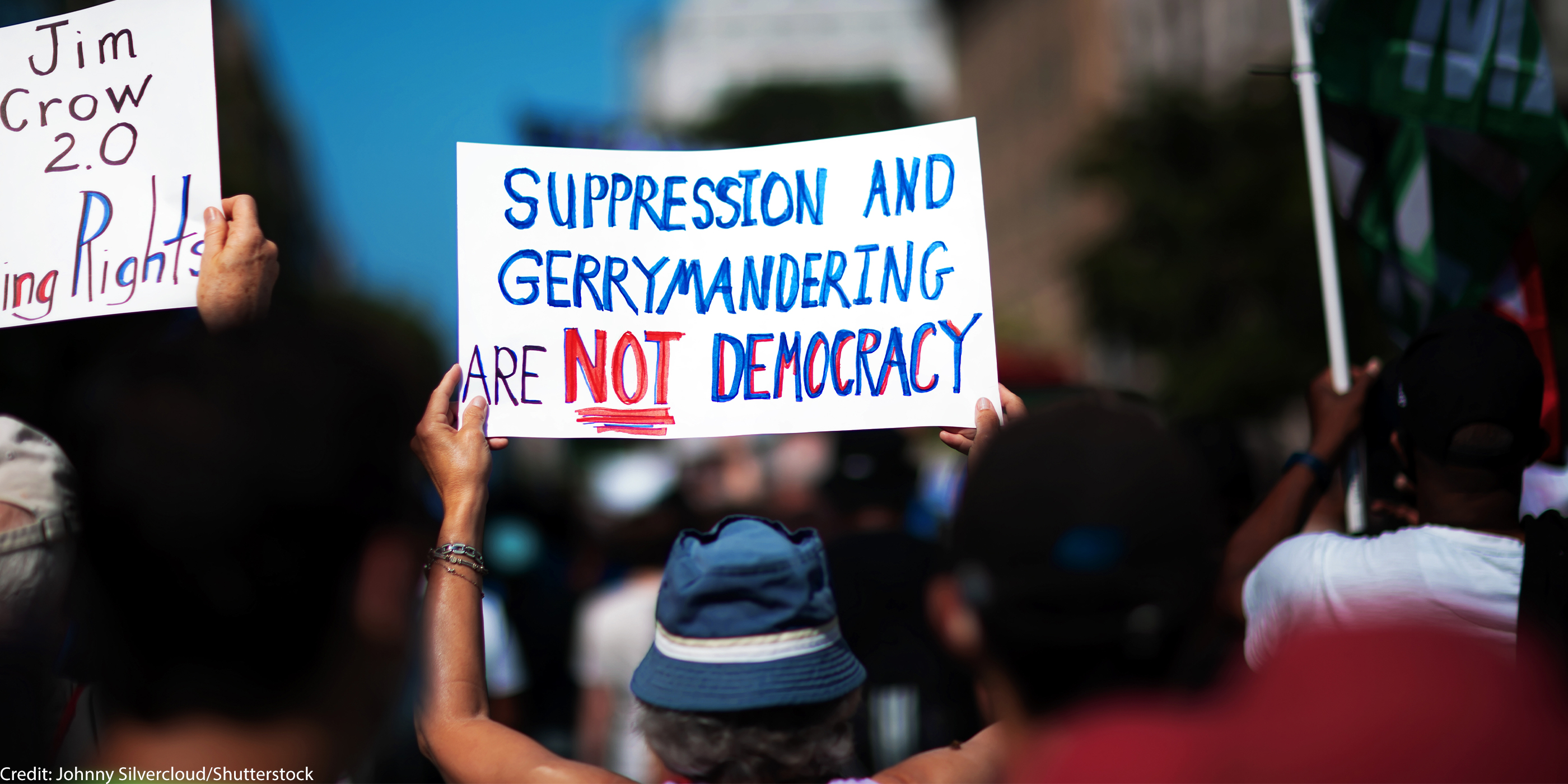 A demonstrator at the March On for Voting Rights in Washington D.C. holds up a sign reading "Suppression and Gerrymandering are Not Democracy".