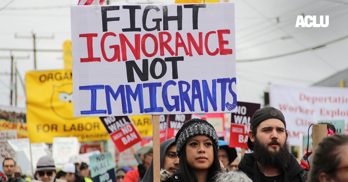 A protester holding a sign with the text &quot;fight ignorance not immigrants&quot;