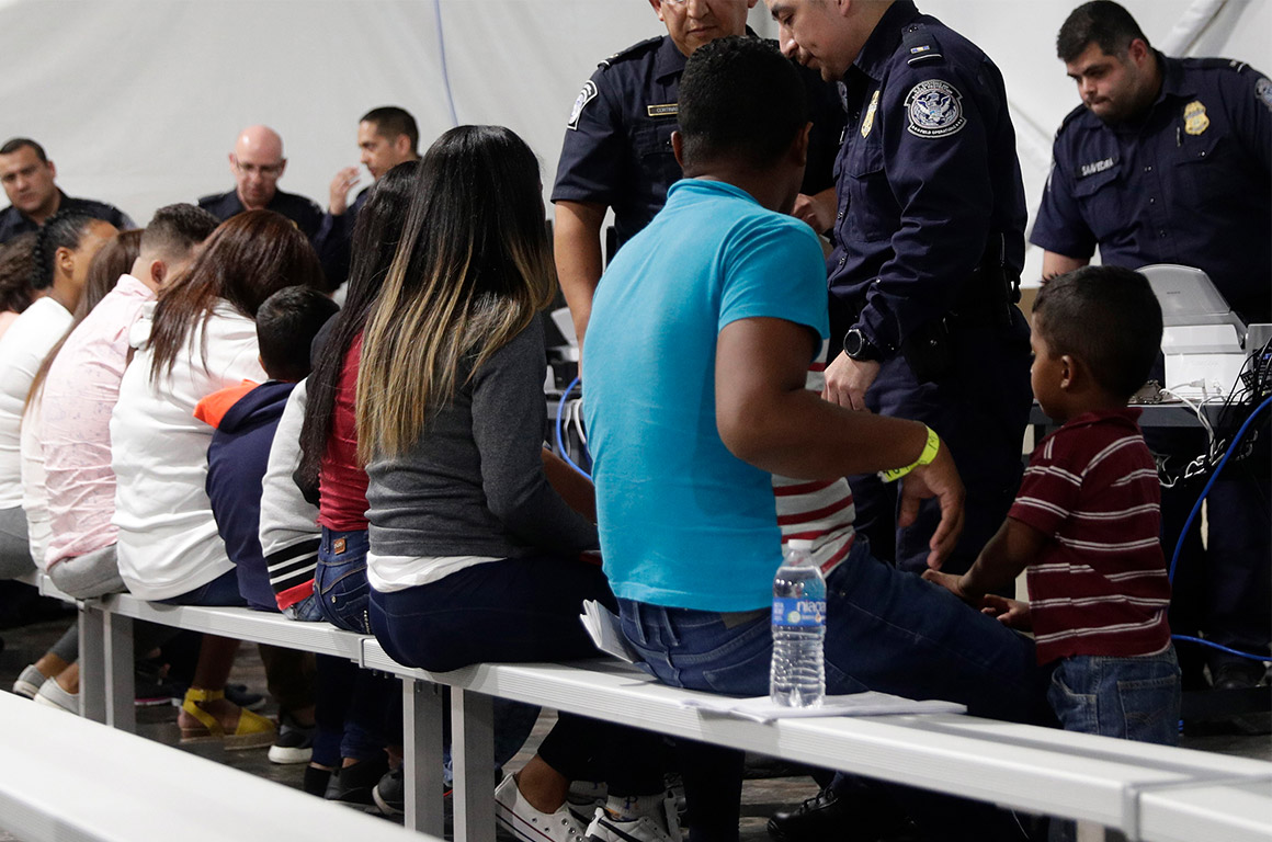 Migrants seated in a processing area at a tent courtroom