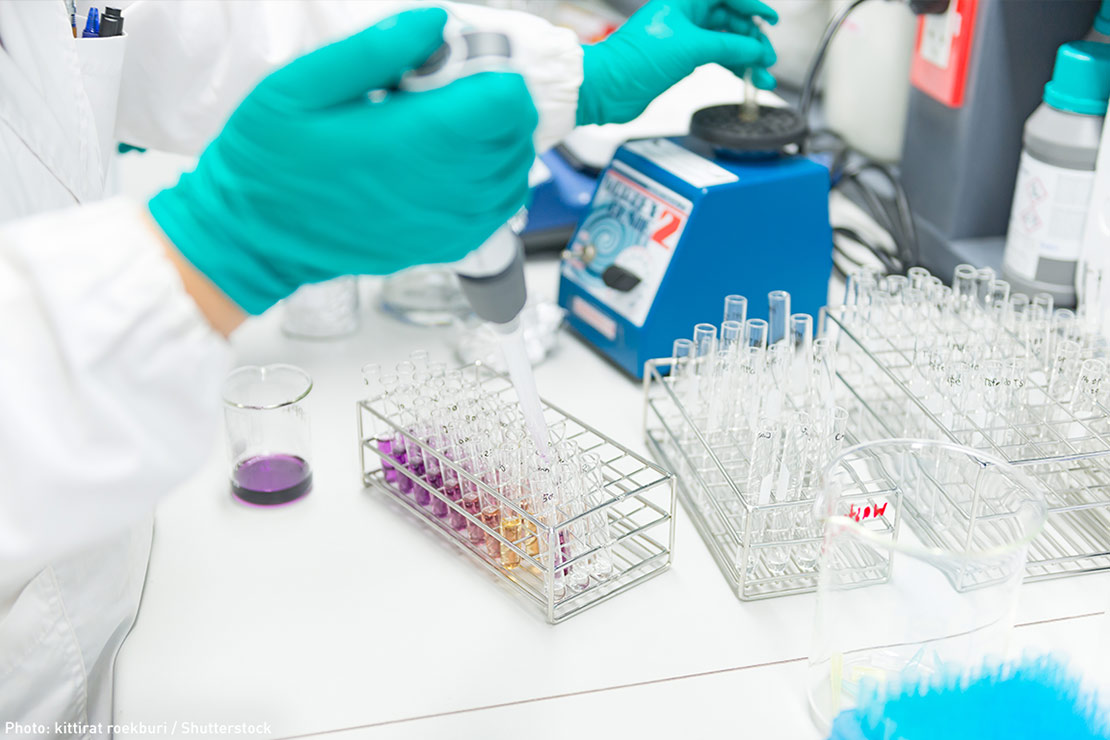 A gloved hand inject fluid into a test tube